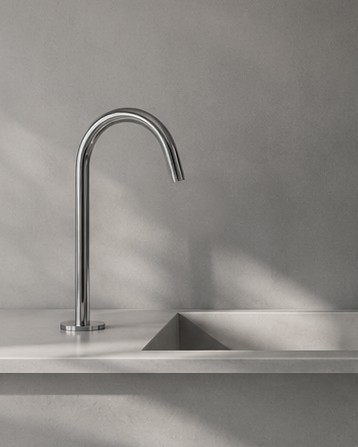 Close-up of a chrome gooseneck faucet over a sculptural stone sink