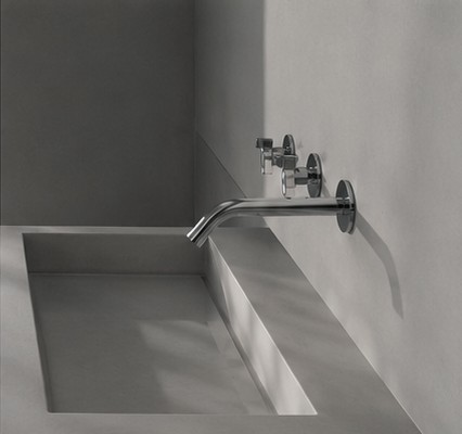 Wall-mounted faucet over a sculptural stone sink